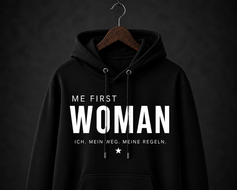 Schwarzer Damen-Statement-Hoodie mit weißem ME FIRST WOMAN Schriftzug auf dunklem Hintergrund.