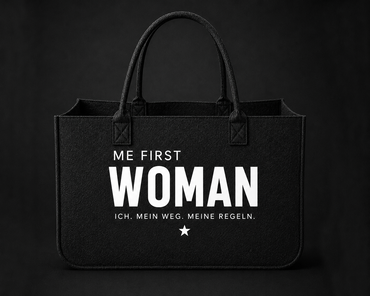 Schwarze Filztasche für Frauen mit weißem ME FIRST WOMAN Schriftzug auf dunklem Hintergrund.