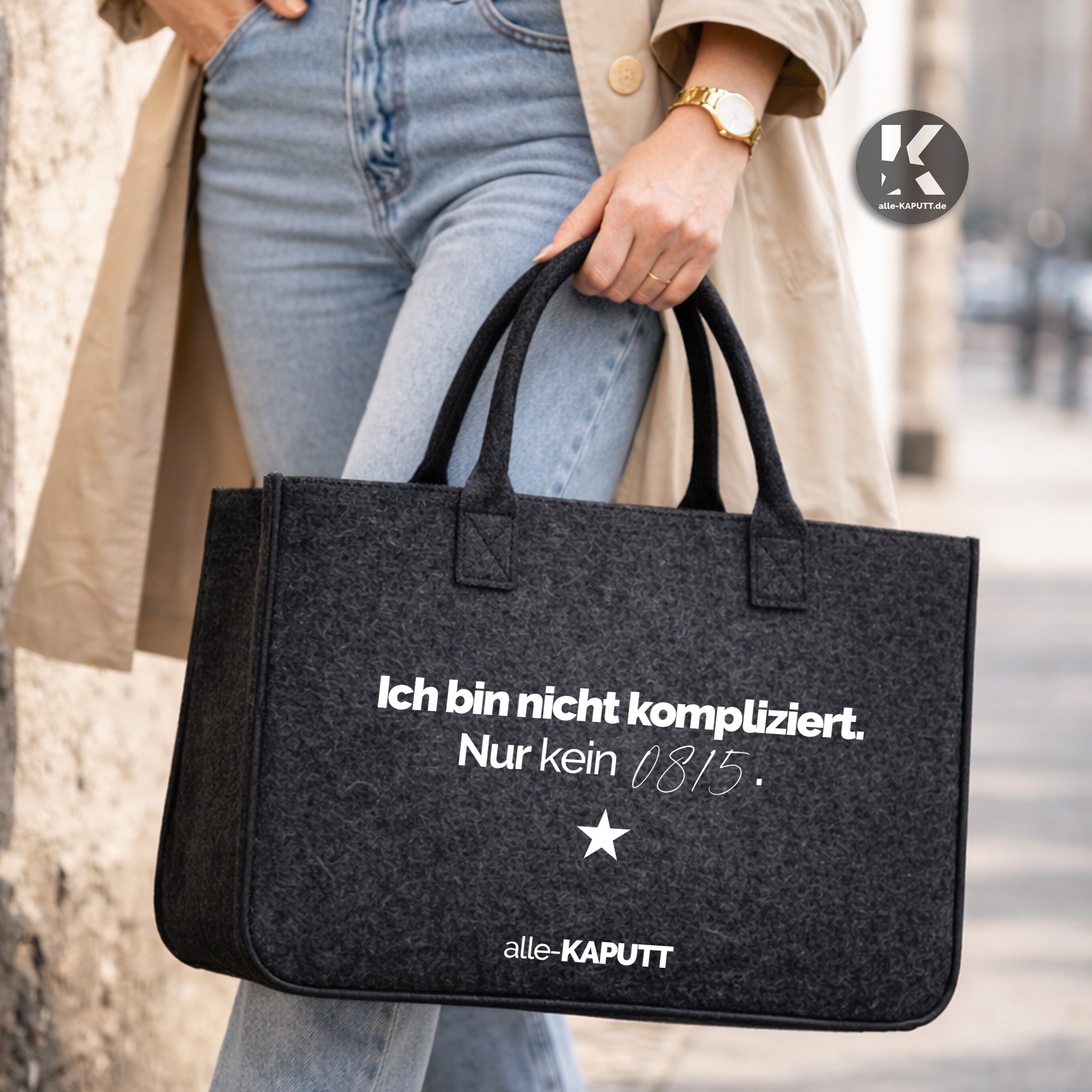 Schwarze Filztasche mit Statement „Ich bin nicht kompliziert. Nur kein 0815.“ im Streetstyle, getragen von einer Frau mit Trenchcoat, Jeans und weißen Sneakern.