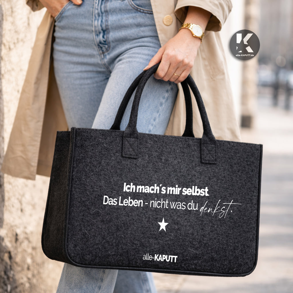 Schwarze Filztasche mit Statement „Ich mach’s mir selbst. Das Leben – nicht was du denkst.“ in der Hand einer Frau im Streetstyle, Marke alle-KAPUTT.