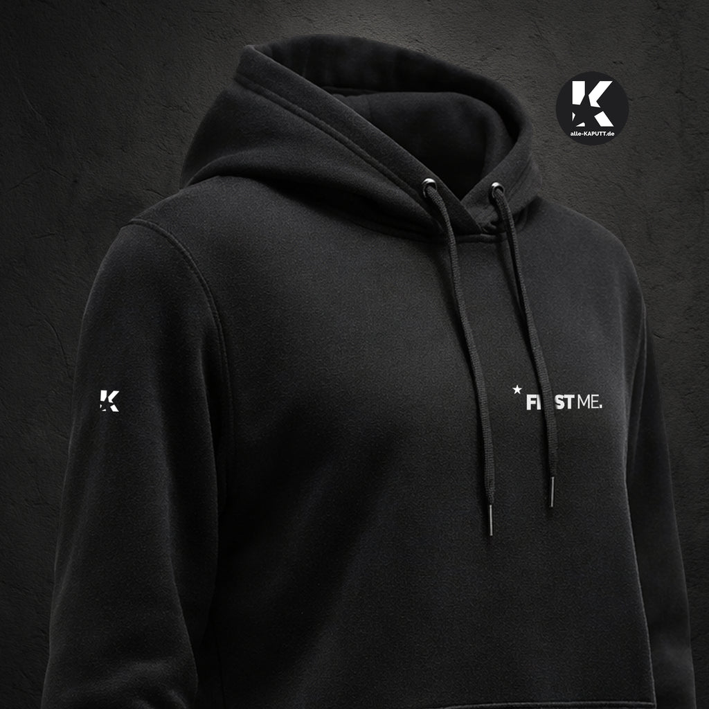 Schräg aufgenommene Vorderansicht eines schwarzen Hoodies mit Statement „FIRST ME.“ und K-Stern am Ärmel aus der First-Me-Collection von alle-KAPUTT