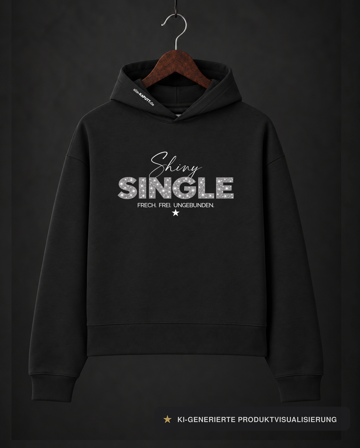 Schwarzer SHINY SINGLE Cropped-Hoodie von alle-KAPUTT mit silbernem Glitzerprint und dem Claim „FRECH. FREI. UNGEBUNDEN.“ am Holzkleiderbügel.