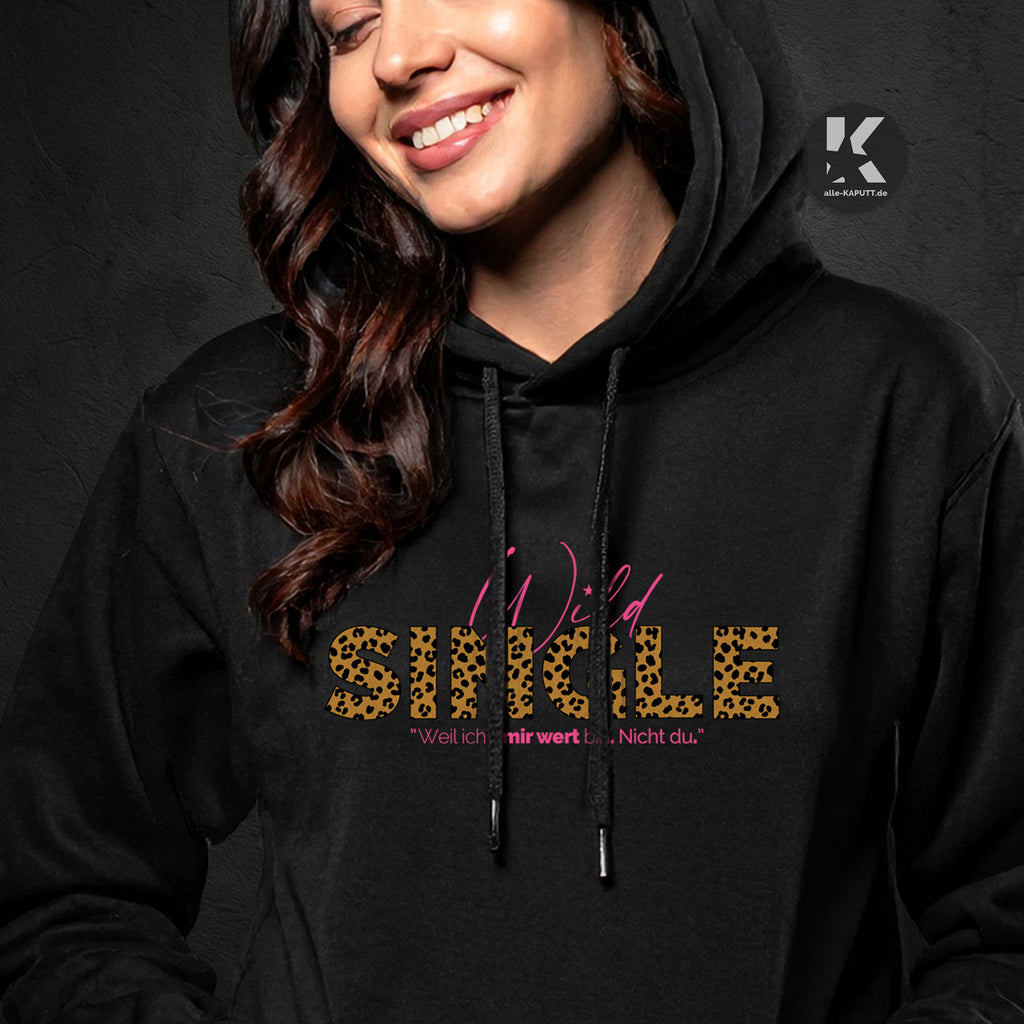 Nahaufnahme eines schwarzen Wild-Single Hoodies von alle-KAPUTT mit Leoparden-Print und dem Statement „Weil ich’s mir wert bin. Nicht du.“. Frau trägt Hoodie und lächelt.